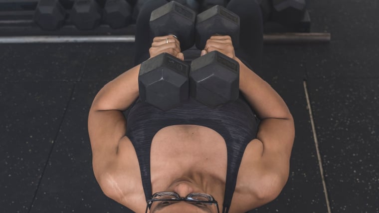 person in gym holding dumbbells on chest